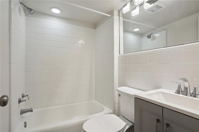 full bathroom with tile walls, vanity, tasteful backsplash, tiled shower / bath, and toilet