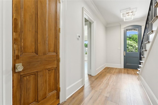 doorway with light hardwood / wood-style floors and ornamental molding