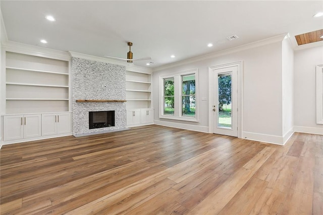 unfurnished living room featuring ornamental molding, ceiling fan, built in features, a fireplace, and light hardwood / wood-style floors