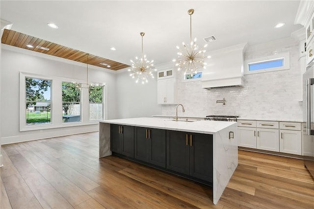 kitchen with wooden ceiling, a kitchen island with sink, hanging light fixtures, custom range hood, and white cabinetry