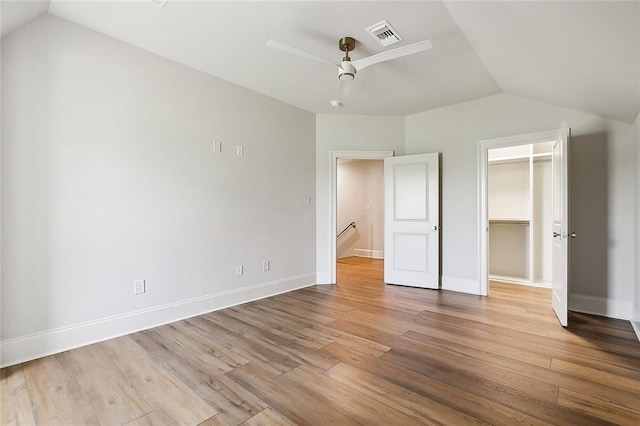 unfurnished bedroom featuring ceiling fan, a spacious closet, light hardwood / wood-style floors, a closet, and lofted ceiling