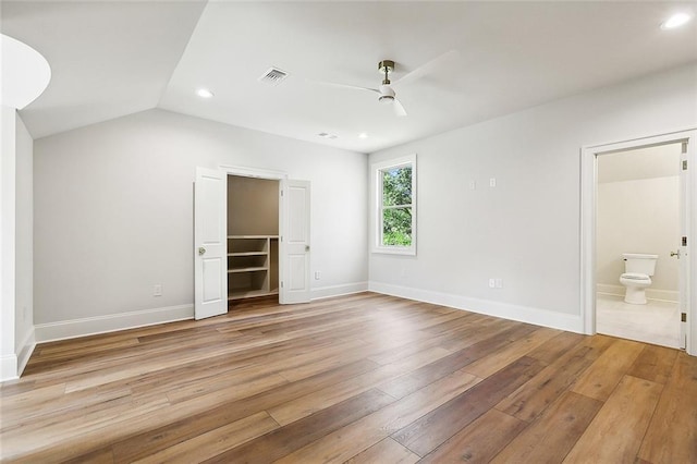 unfurnished bedroom with light wood-type flooring, a spacious closet, ceiling fan, and lofted ceiling