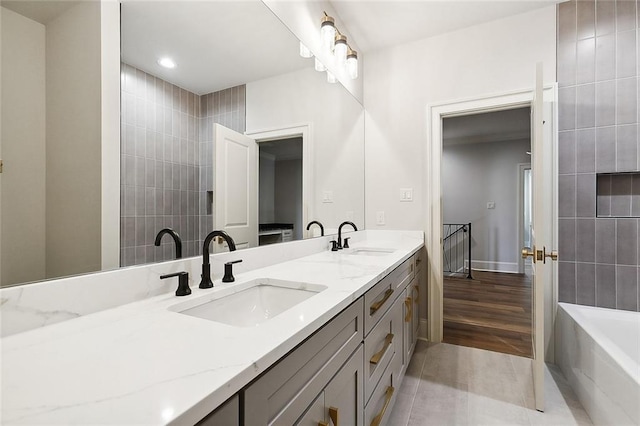 bathroom featuring tile patterned floors, vanity, and tiled bath