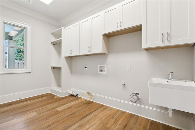 washroom featuring cabinets, light hardwood / wood-style flooring, hookup for a gas dryer, and ornamental molding