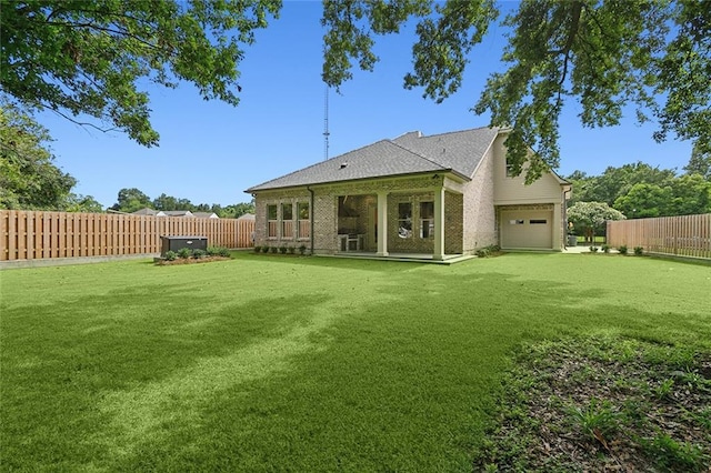 back of house featuring a lawn and a garage