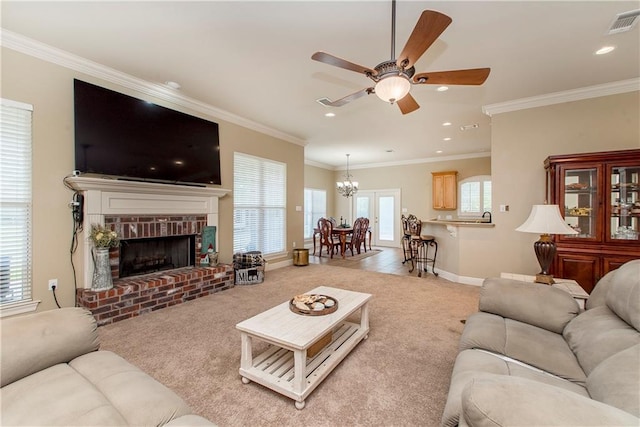 living room with ornamental molding, a fireplace, carpet floors, and ceiling fan with notable chandelier