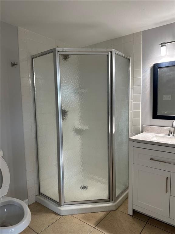 bathroom featuring a shower with shower door, vanity, tile patterned flooring, and toilet