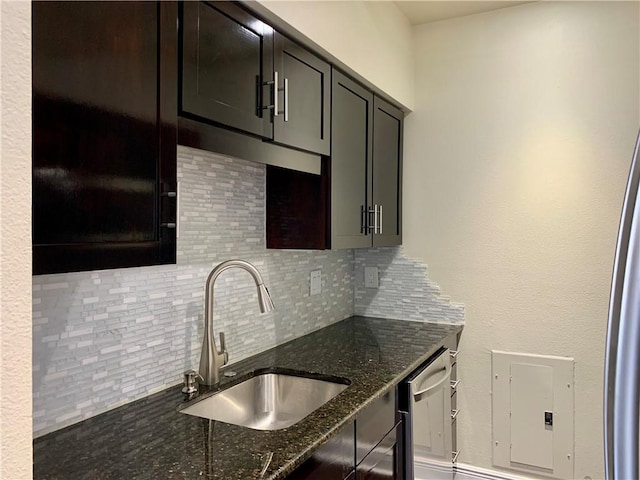 kitchen featuring tasteful backsplash, stainless steel dishwasher, sink, and dark stone countertops