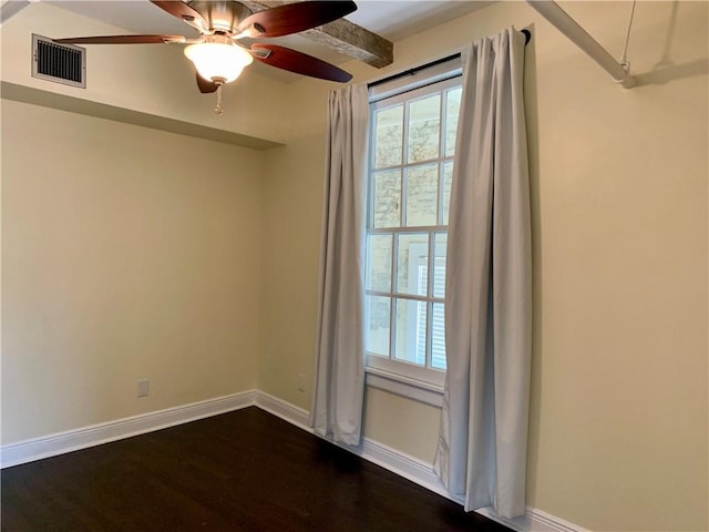 spare room featuring ceiling fan, plenty of natural light, dark hardwood / wood-style flooring, and beam ceiling