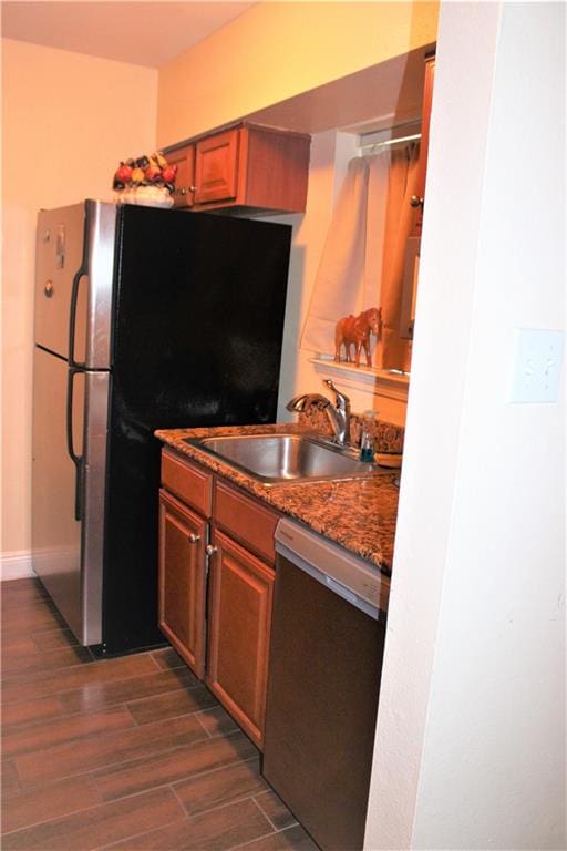 kitchen with dark stone counters, dark hardwood / wood-style flooring, sink, dishwasher, and fridge