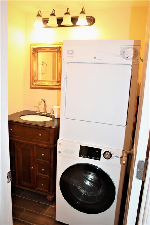 laundry area with stacked washer and clothes dryer and sink