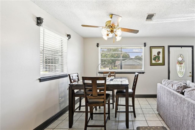 tiled dining room with a textured ceiling and ceiling fan