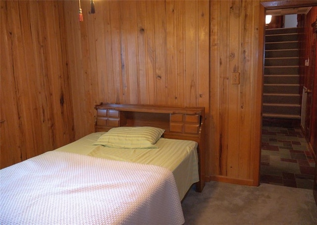 carpeted bedroom featuring wood walls