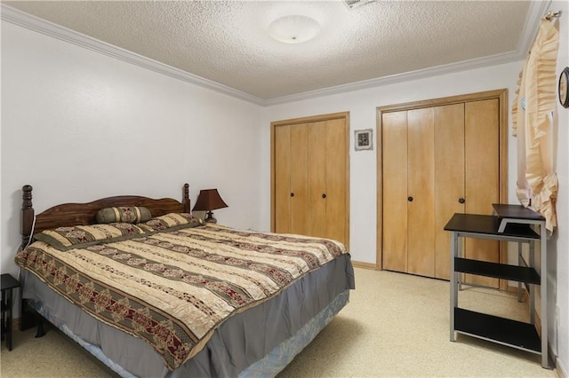 bedroom with a textured ceiling, ornamental molding, and two closets