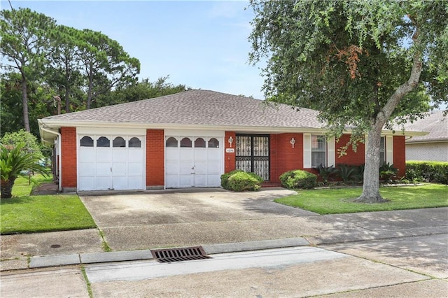 single story home featuring a front yard, concrete driveway, brick siding, and an attached garage