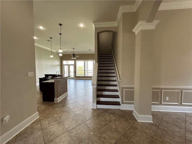 stairs featuring tile patterned flooring, decorative columns, crown molding, and sink