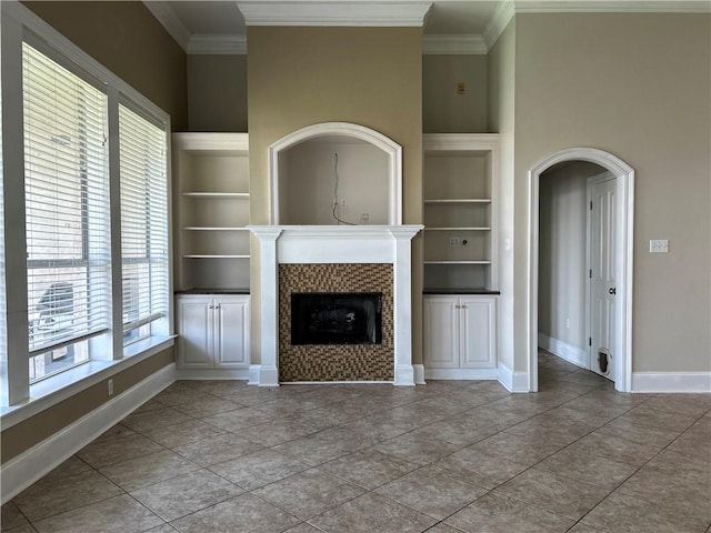 unfurnished living room featuring a fireplace, built in shelves, and tile patterned flooring