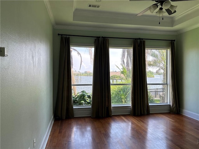 spare room featuring ceiling fan, dark wood-type flooring, a raised ceiling, and ornamental molding