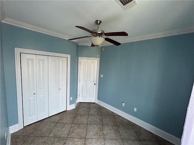 unfurnished bedroom with a closet, dark tile patterned floors, ceiling fan, and crown molding