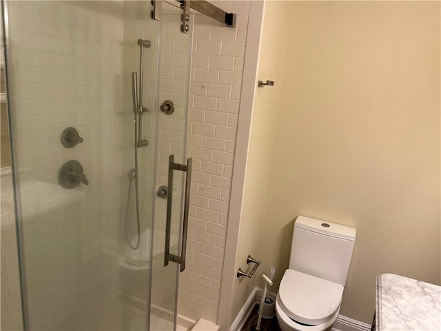 bathroom featuring toilet and a shower with door