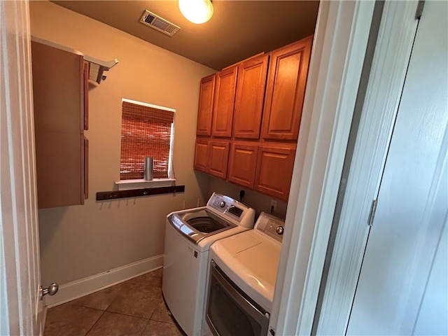 clothes washing area with cabinets, dark tile patterned floors, and washing machine and dryer