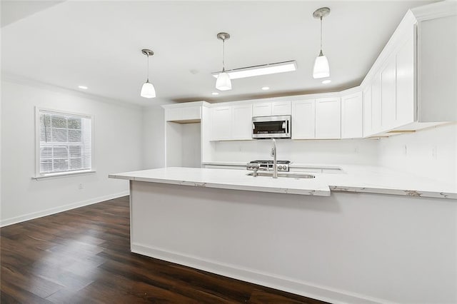 kitchen with white cabinetry, dark hardwood / wood-style flooring, light stone counters, and decorative light fixtures