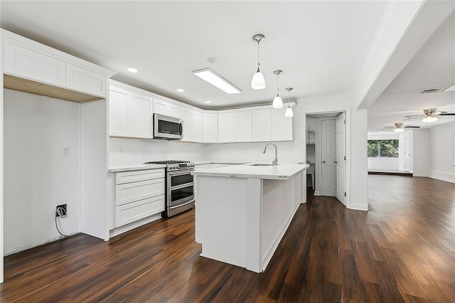 kitchen featuring ceiling fan, stainless steel appliances, pendant lighting, a kitchen island with sink, and white cabinets