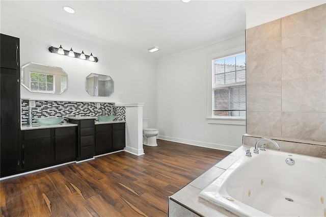 bathroom with vanity, hardwood / wood-style flooring, toilet, ornamental molding, and tiled tub