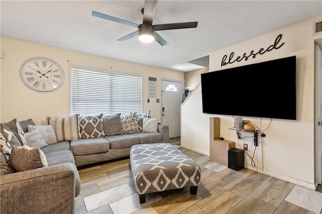 living room with wood tiled floor, visible vents, a textured ceiling, and a ceiling fan