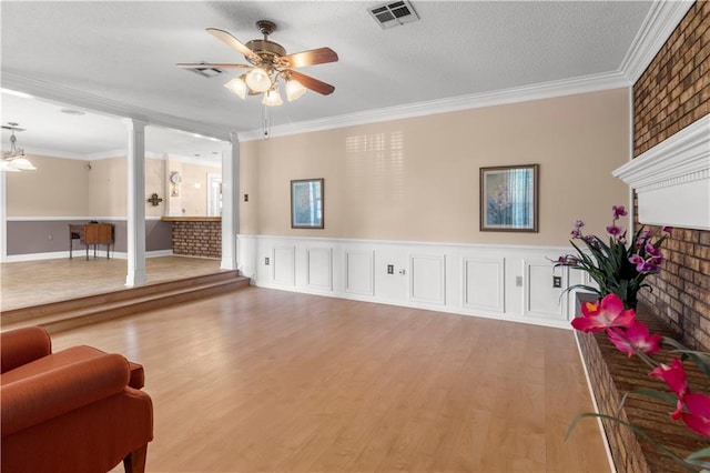 living room with hardwood / wood-style flooring, crown molding, decorative columns, and ceiling fan