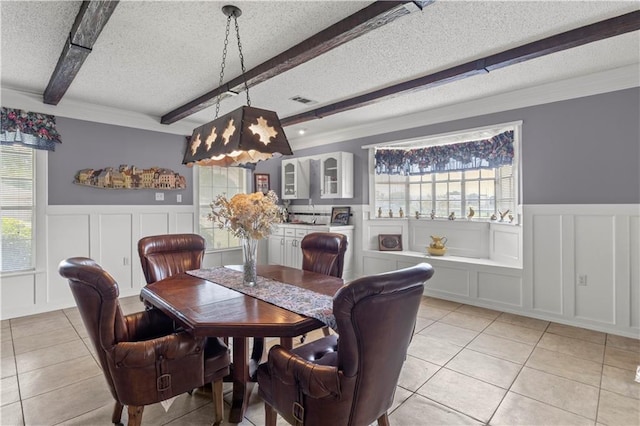 tiled dining space featuring beamed ceiling and a textured ceiling