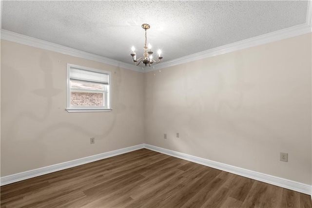 spare room with a textured ceiling, crown molding, dark hardwood / wood-style floors, and a chandelier