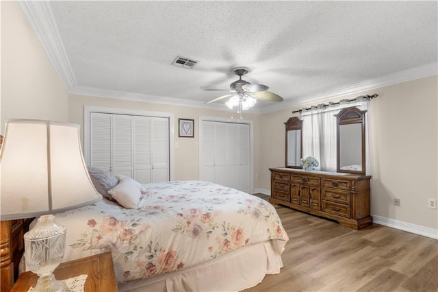 bedroom with crown molding, a textured ceiling, ceiling fan, multiple closets, and wood-type flooring