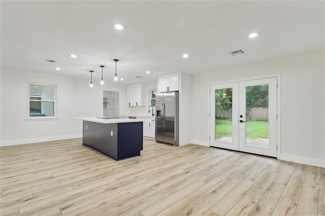 kitchen featuring white cabinetry, stainless steel fridge with ice dispenser, light wood-type flooring, and a kitchen island