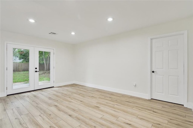 spare room featuring french doors and light hardwood / wood-style flooring