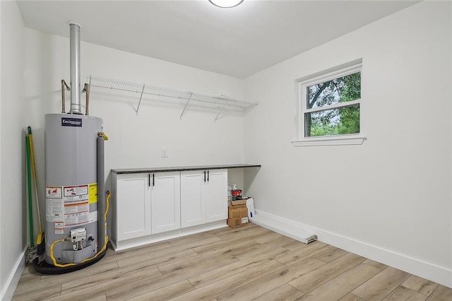 laundry area featuring water heater and light hardwood / wood-style flooring