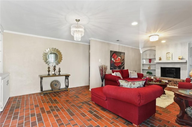 living room featuring brick wall, ornamental molding, a brick fireplace, and a notable chandelier