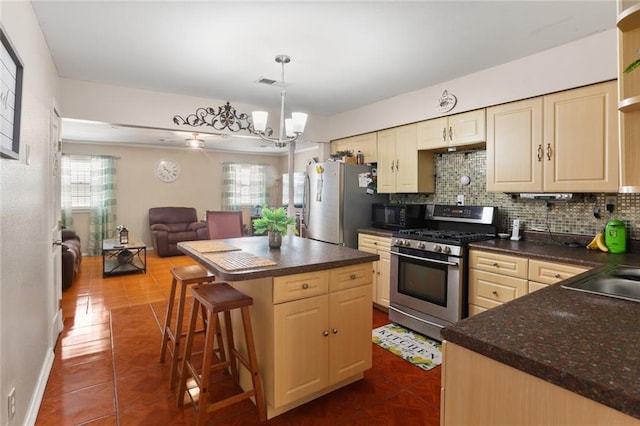 kitchen featuring a notable chandelier, hanging light fixtures, decorative backsplash, appliances with stainless steel finishes, and dark tile patterned flooring