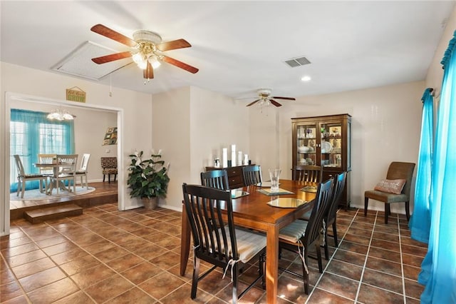 dining area featuring ceiling fan with notable chandelier and dark tile patterned flooring