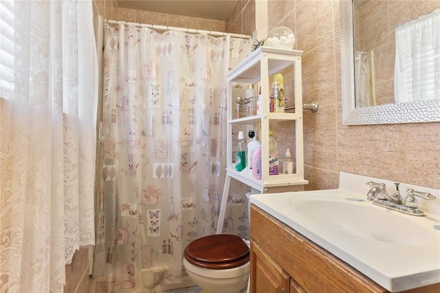 bathroom with vanity, tile walls, and toilet