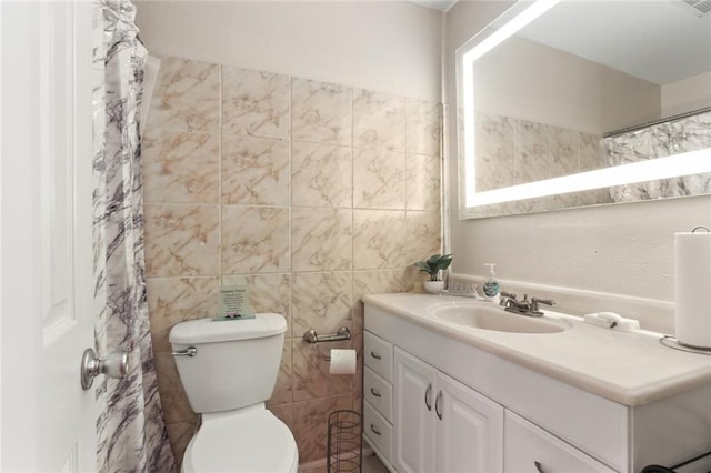 bathroom featuring vanity, toilet, and tile walls