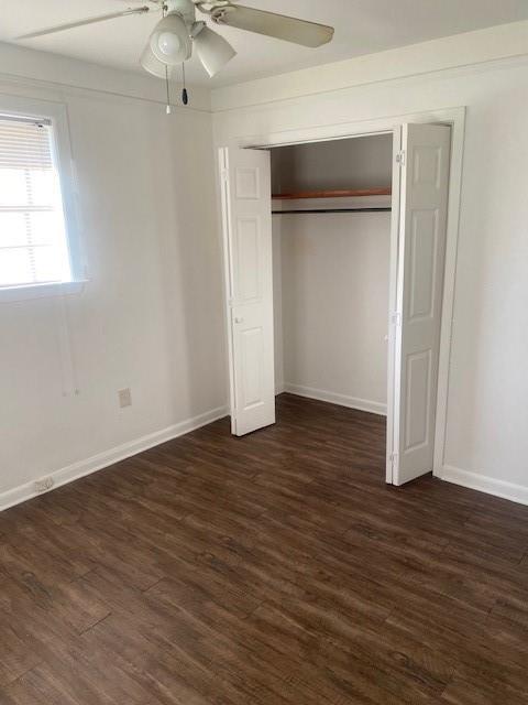 unfurnished bedroom featuring dark wood-type flooring, a closet, and ceiling fan