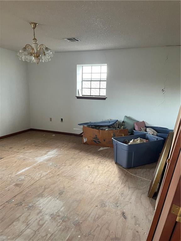 empty room with a chandelier and a textured ceiling