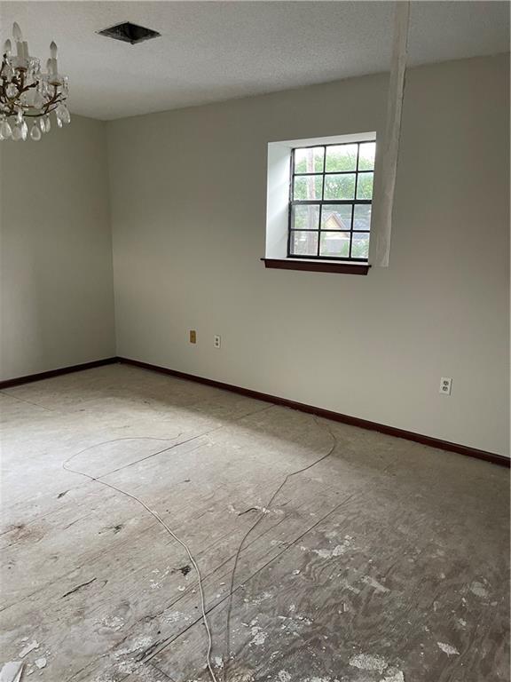 unfurnished room featuring a chandelier and a textured ceiling