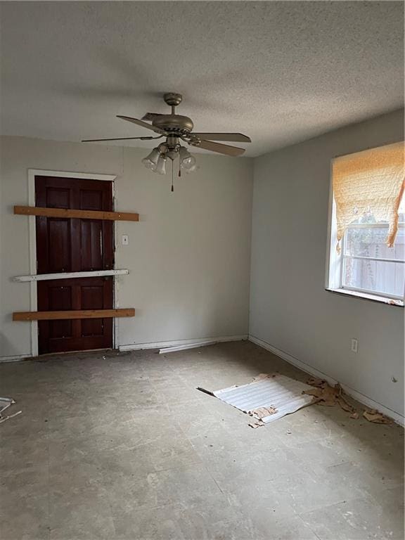 unfurnished room with ceiling fan and a textured ceiling