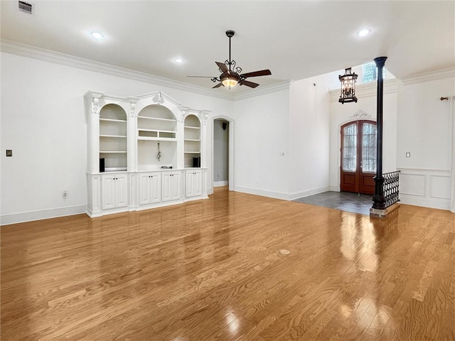 unfurnished living room with ceiling fan with notable chandelier, french doors, light wood-type flooring, and crown molding