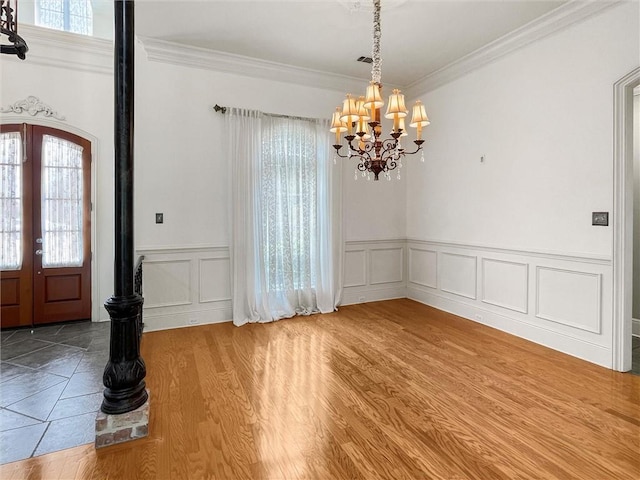 entryway with hardwood / wood-style flooring, ornamental molding, french doors, and a chandelier