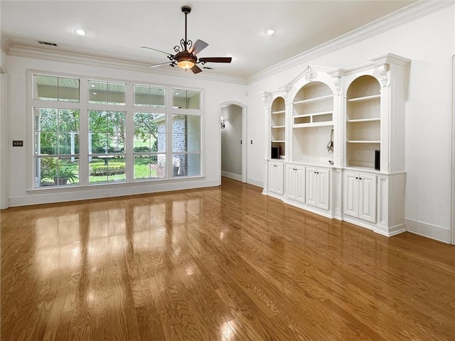 unfurnished living room featuring ceiling fan, wood-type flooring, and ornamental molding