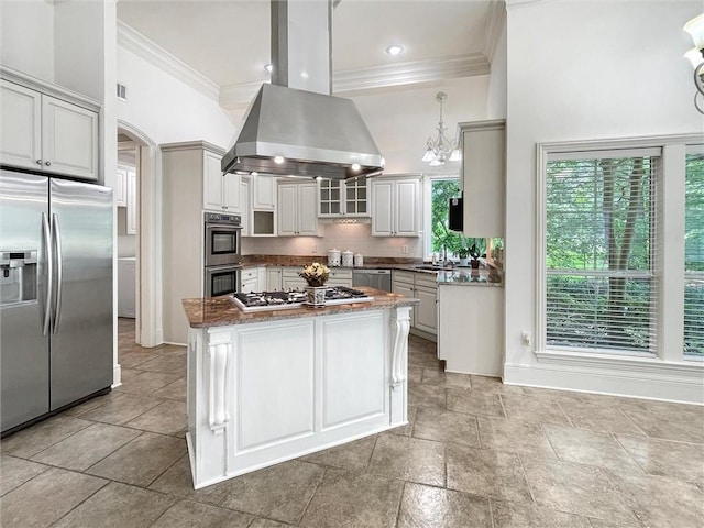 kitchen featuring sink, hanging light fixtures, island exhaust hood, dark stone counters, and appliances with stainless steel finishes