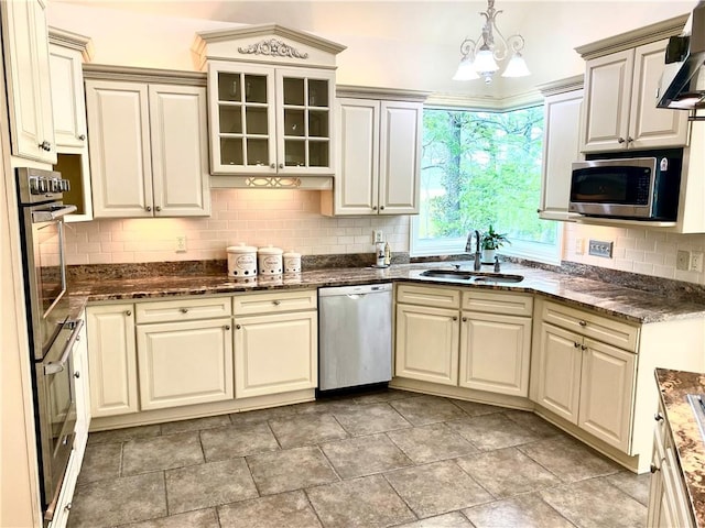 kitchen with hanging light fixtures, decorative backsplash, sink, and stainless steel appliances